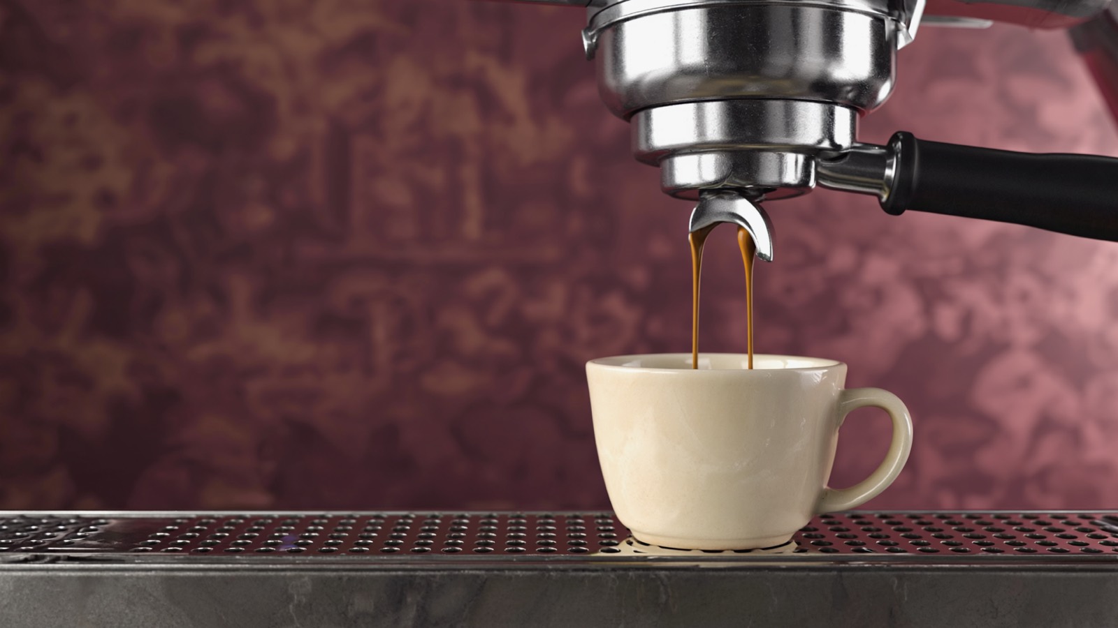 Ein frisch gezogener Espresso läuft in zwei dünnen, honigfarbenen Strängen in eine vorgewärmte Tasse.